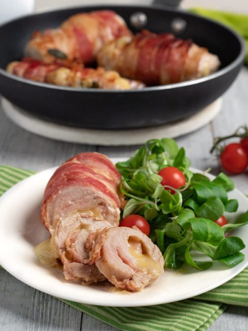 Involtini di tacchino avvolti nella pancetta, affettati e serviti con valeriana e pomodorini ciliegino