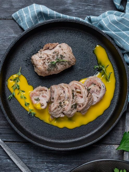 Involtini di vitello affettati con salsa dorata e timo fresco in padella di ferro