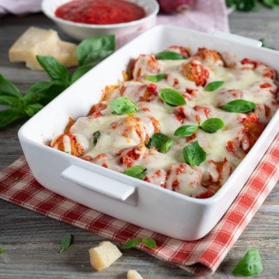 Polpette filanti al sugo coperte di mozzarella fusa e foglie di basilico fresco