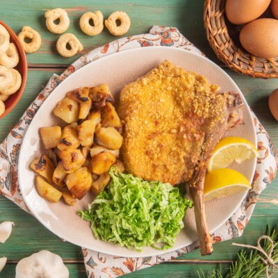 Costoletta di vitello con panatura di taralli servita con patate rosolate, insalata e spicchi di limone