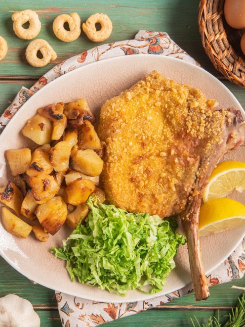 Costoletta di vitello con panatura di taralli servita con patate rosolate, insalata e spicchi di limone
