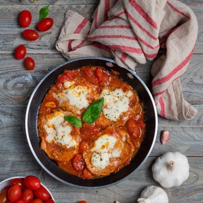 Fettine di vitello alla pizzaiola in padella con mozzarella filante, pomodorini e basilico fresco