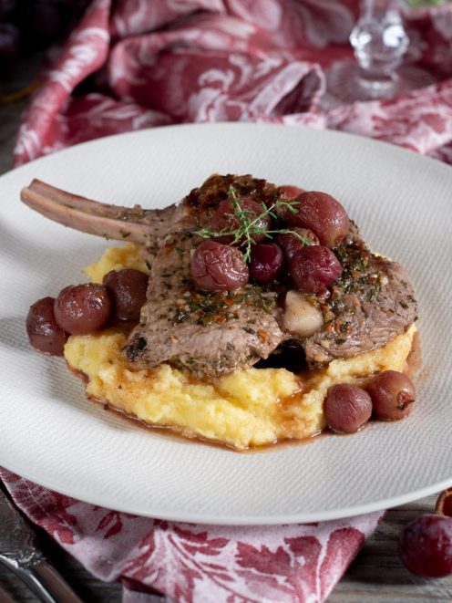 Costolette di vitello con uva su letto di polenta cremosa, guarnite con timo fresco e fondo di cottura
