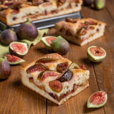 Focaccia con i fichi tagliata a fette, con polpa succosa in vista e fichi freschi tutt'intorno