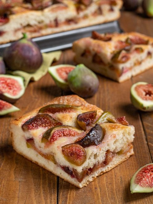 Focaccia con i fichi tagliata a fette, con polpa succosa in vista e fichi freschi tutt'intorno