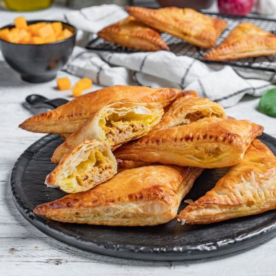 Hand pies di pasta sfoglia dorata farciti con carne macinata e zucca, tagliati a meta
