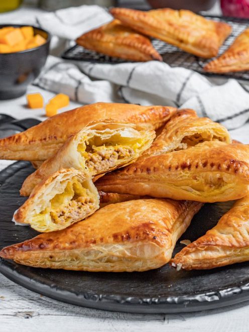 Hand pies di pasta sfoglia dorata farciti con carne macinata e zucca, tagliati a meta