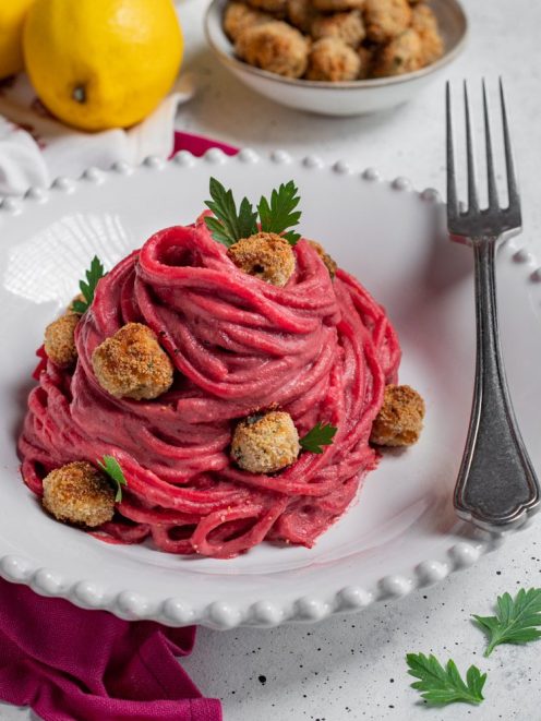 Pasta alla barbabietola con polpettine panate disposte a nido, guarnita con foglie di prezzemolo
