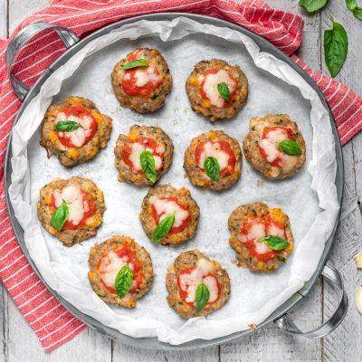 Pizzette di carne al forno con pomodoro, mozzarella filante e foglie di basilico fresco