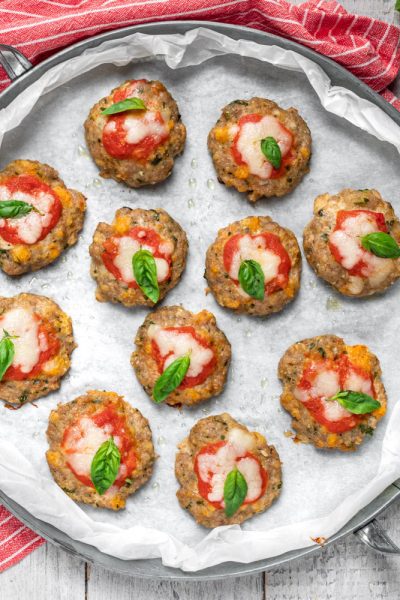 Pizzette di carne al forno con pomodoro, mozzarella filante e foglie di basilico fresco