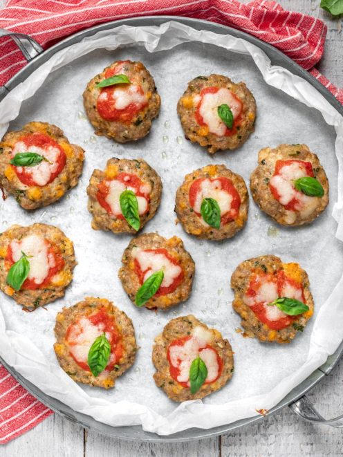 Pizzette di carne al forno con pomodoro, mozzarella filante e foglie di basilico fresco
