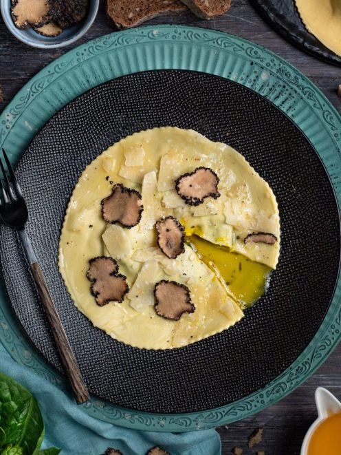Raviolone con tuorlo fondente aperto, lamelle di tartufo nero e scaglie di parmigiano