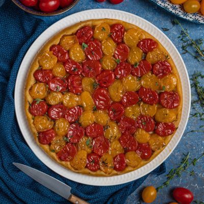 Tart tatin salata con pomodorini rossi e gialli arrostiti, guarnita con foglioline di timo