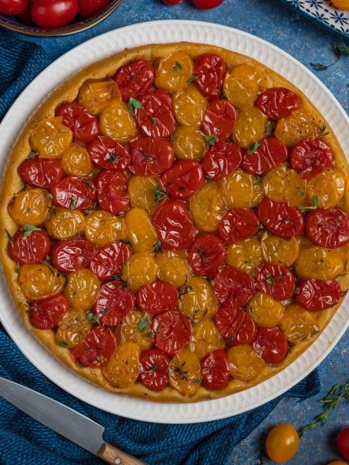 Tart tatin salata con pomodorini rossi e gialli arrostiti, guarnita con foglioline di timo