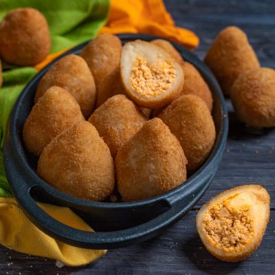 Coxinha fritte dorate servite in ciotola, con una tagliata a metà che rivela il ripieno