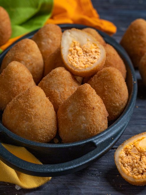 Coxinha fritte dorate servite in ciotola, con una tagliata a metà che rivela il ripieno