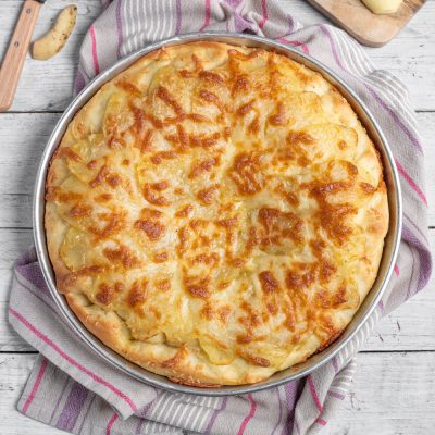Focaccia con formaggio e patate appena sfornata, con superficie dorata e gratinata
