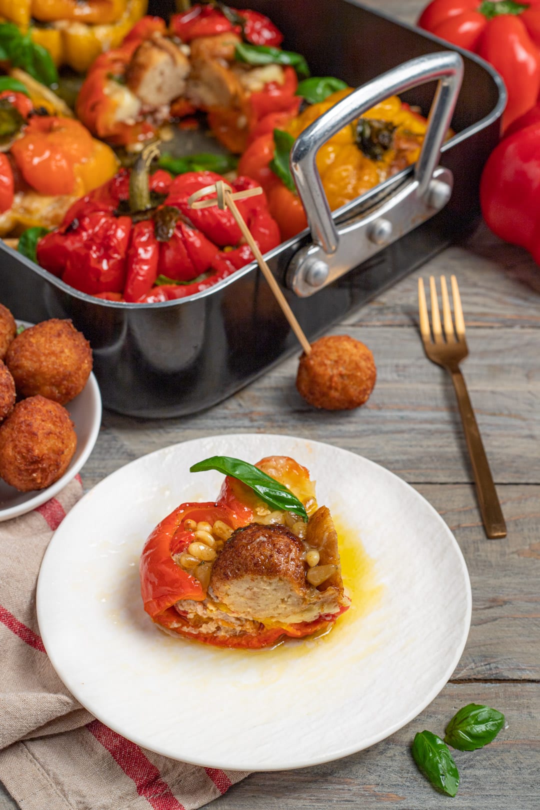 Peperone ripieno di vitello con pinoli e basilico servito accanto alla teglia con gli altri peperoni