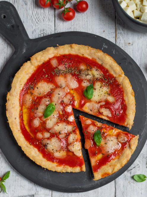 Pizza di tacchino con salsa di pomodoro, mozzarella sciolta e foglie di basilico fresco, una fetta già tagliata