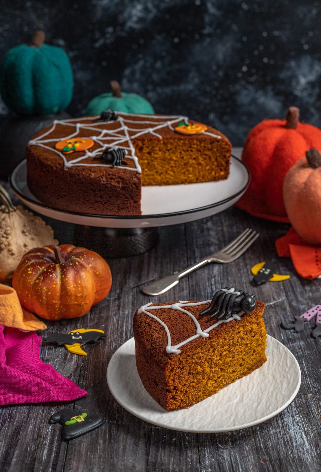 Fetta di torta di zucca con glassa a ragnatela e ragnetto di zucchero in primo piano