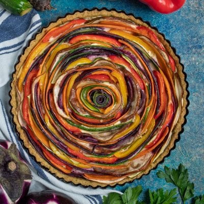 Torta salata di verdure a spirale con fettine di zucchine, peperoni e melanzane disposte a rosone su base integrale