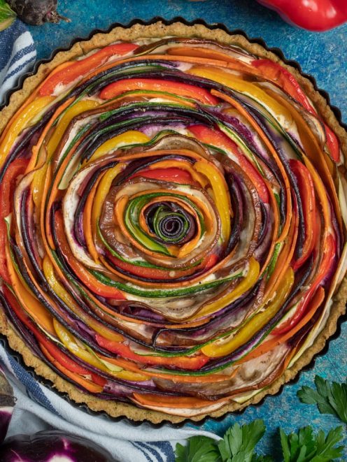 Torta salata di verdure a spirale con fettine di zucchine, peperoni e melanzane disposte a rosone su base integrale