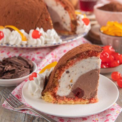 Zuccotto toscano in fetta con ripieno di crema al cioccolato, panna e ciliegie candite