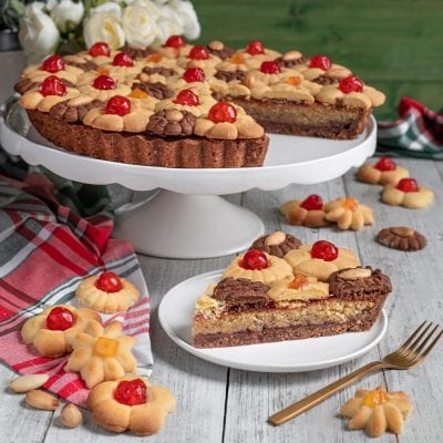 Crostata bicolore con biscotti alle ciliegie candite, servita a fette con strati di pasta frolla chiara e al cacao