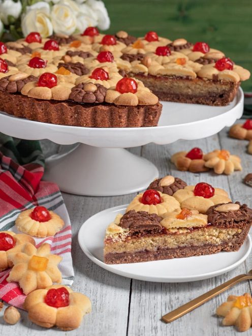 Crostata bicolore con biscotti alle ciliegie candite, servita a fette con strati di pasta frolla chiara e al cacao