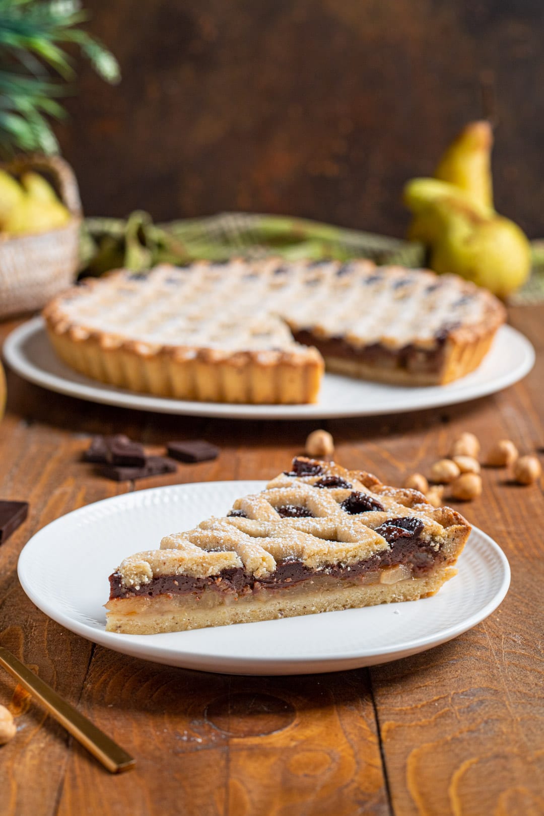Fetta di crostata cioccolato e pere con reticolo di frolla spolverato di zucchero a velo, ripieno a strati ben visibile