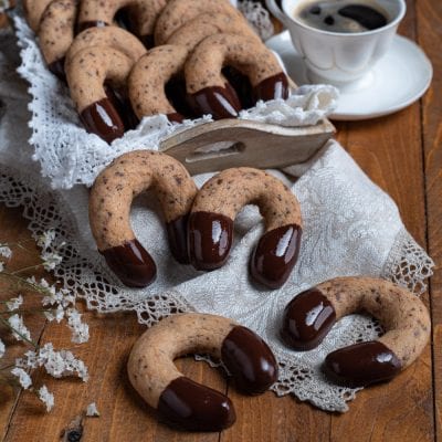Kipferl al cioccolato a forma di ferro di cavallo con punte glassate su tovagliolo di pizzo