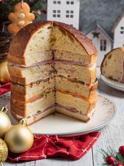 Panettone gastronomico farcito a strati con salumi, formaggi cremosi e verdure grigliate, tagliato a meta