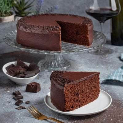 Torta al vino rosso ricoperta di glassa al cioccolato con codette e una fetta servita a parte