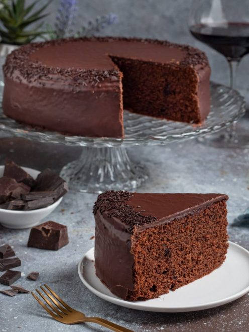 Torta al vino rosso ricoperta di glassa al cioccolato con codette e una fetta servita a parte