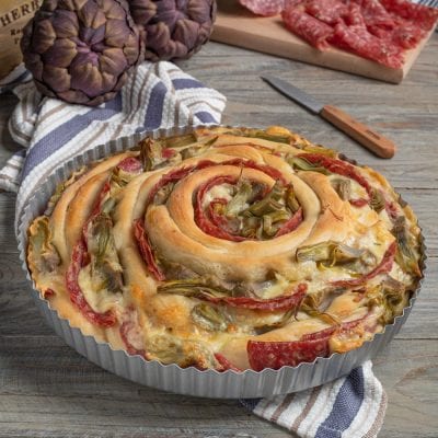 Torta spirale di panfocaccia con carciofi e salame disposti a chiocciola, filante di formaggio fuso