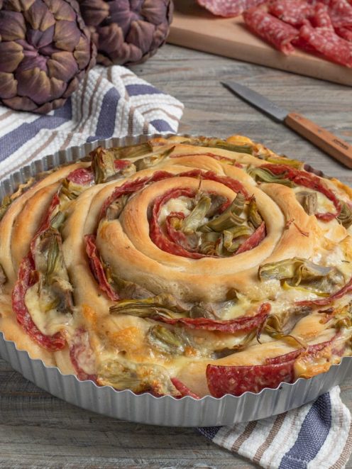 Torta spirale di panfocaccia con carciofi e salame disposti a chiocciola, filante di formaggio fuso
