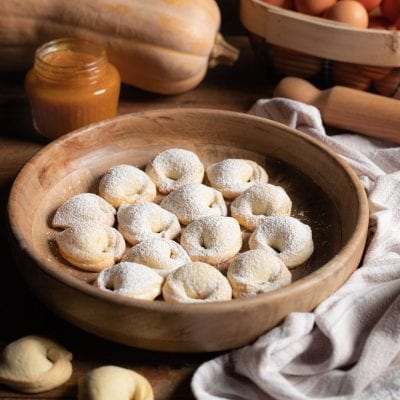 Cappellacci dolci alla zucca spolverati di zucchero a velo, serviti in ciotola di legno