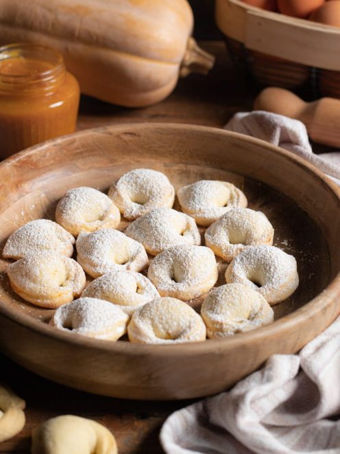Cappellacci dolci alla zucca spolverati di zucchero a velo, serviti in ciotola di legno
