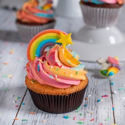 Cupcake arcobaleno con glassa swirl multicolore, decorazione a stella e zuccherini colorati