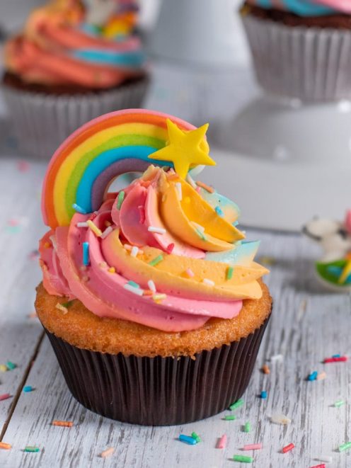 Cupcake arcobaleno con glassa swirl multicolore, decorazione a stella e zuccherini colorati