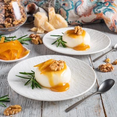 Panna cotta salata con colatura al miele, gherigli di noce e scorze d'arancia candite su rametti di rosmarino