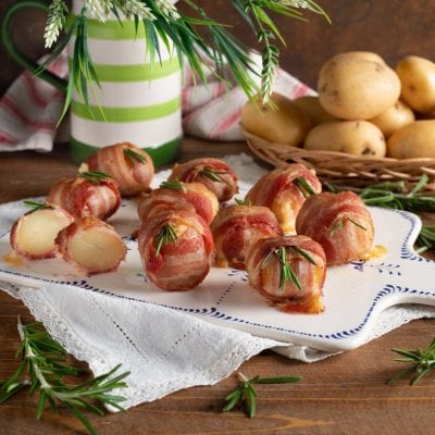 Bocconcini di patate, formaggio e bacon avvolti e guarniti con rametti di rosmarino