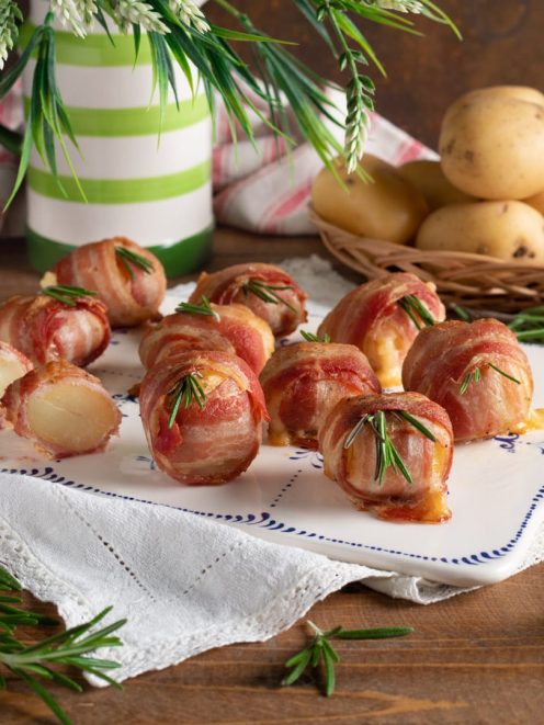 Bocconcini di patate, formaggio e bacon avvolti e guarniti con rametti di rosmarino