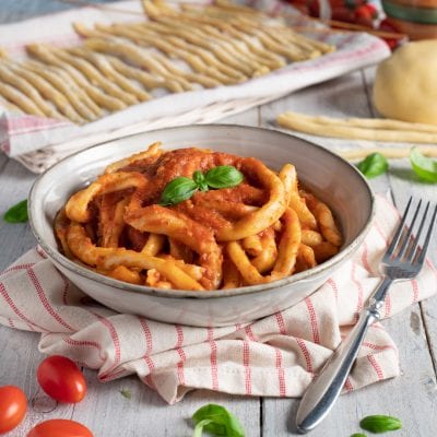 Mparrettati calabresi conditi con sugo di pomodoro denso e guarnito con foglie di basilico fresco