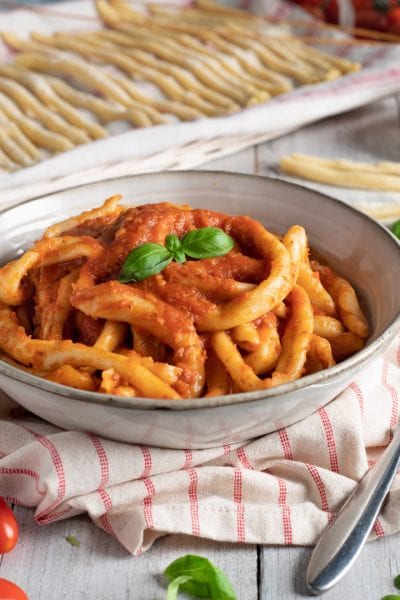 Mparrettati calabresi conditi con sugo di pomodoro denso e guarnito con foglie di basilico fresco