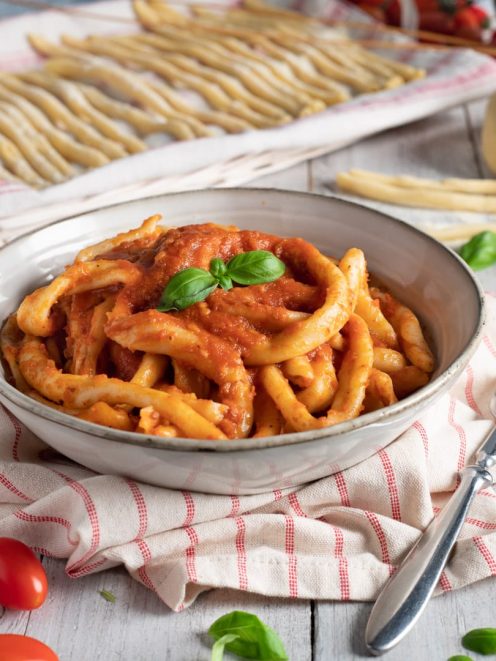 Mparrettati calabresi conditi con sugo di pomodoro denso e guarnito con foglie di basilico fresco