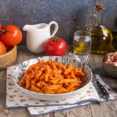 Penne alla vodka condite con salsa di pomodoro cremosa e pancetta a cubetti