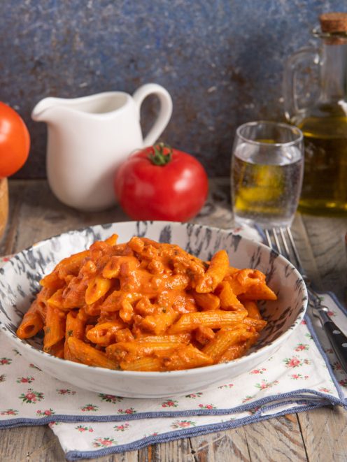 Penne alla vodka condite con salsa di pomodoro cremosa e pancetta a cubetti
