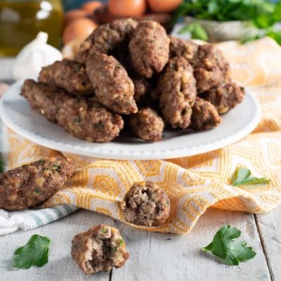 Polpette vrasciole calabresi allungate impilate sul piatto con una tagliata a meta per mostrare l'interno