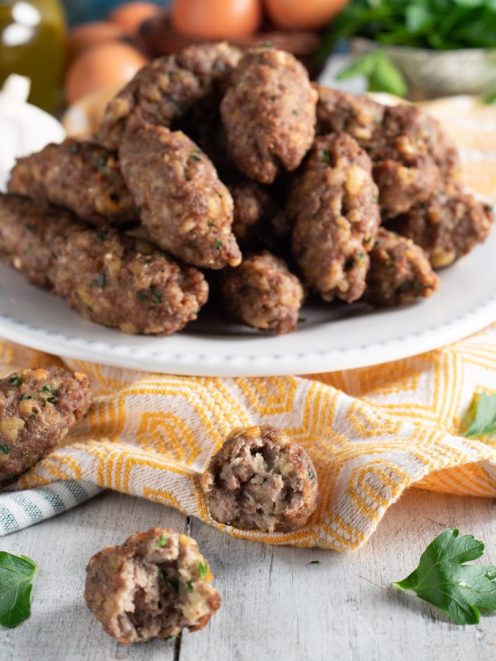 Polpette vrasciole calabresi allungate impilate sul piatto con una tagliata a meta per mostrare l'interno